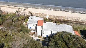 Propiedad costera con vista a la playa, un camino pavimentado y una pequeña escalera que conduce a la entrada.