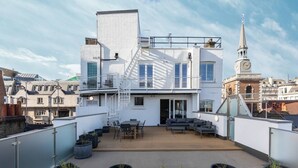 En takterrass med modern design, med ett trädäck, utemöbler och krukväxter.