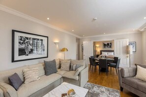 A living room with a sofa, coffee table, and framed pictures on the wall. - Stylish apartment with terrace in Mayfair (London)