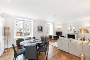 A modern living room with a dining area, a fireplace, and large windows. - Stylish apartment with terrace in Mayfair (London)