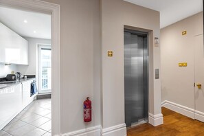 A hallway with a fire extinguisher, an elevator, and a door with a lock. - Stylish apartment with terrace in Mayfair (London)