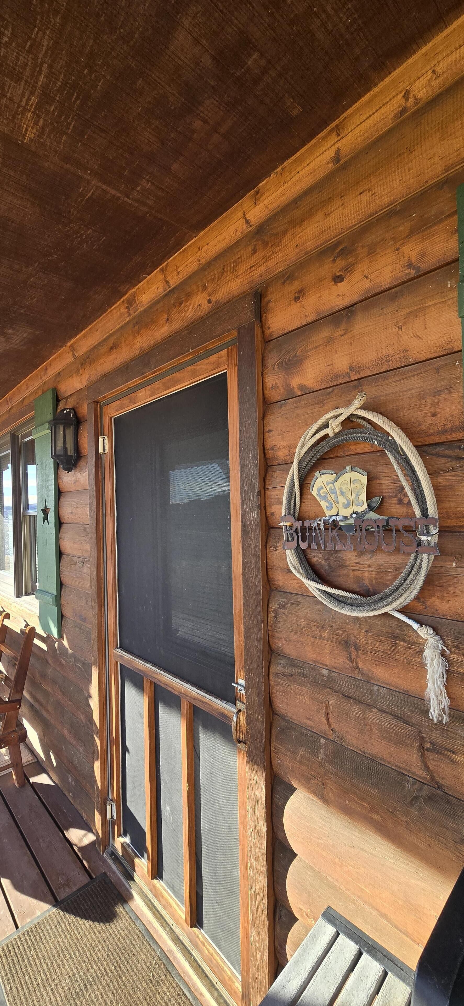 Eine Holzhütte mit großem Fenster, einer Tür und einem rustikalen Schild.