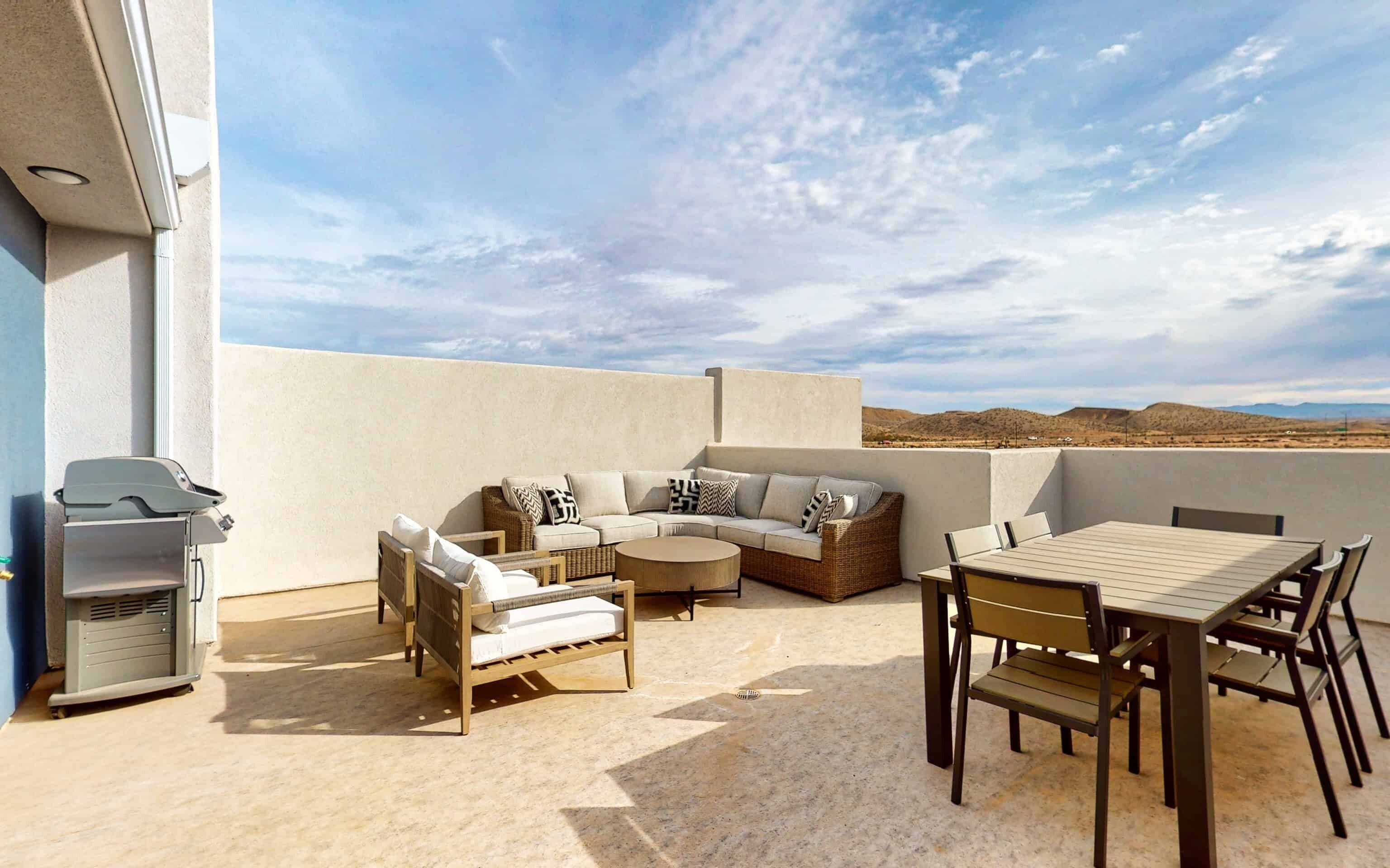 An outdoor patio with a sofa set, a dining table, and a grill.