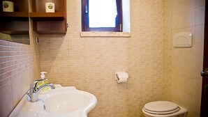 Een badkamer met een wastafel, toilet en een raam.