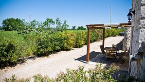 Een rustieke buitenruimte met een pergola, een stenen muur en een tafel met stoelen.
