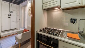 A kitchen with a gas stove, white cabinets, and a sink. - Quiet and cozy, by Campo de’ Fiori (Roma)