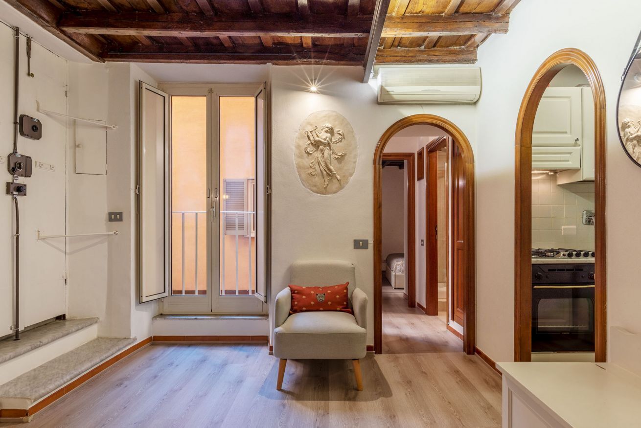 Un vaste salon doté d’un plafond en bois, d’une cheminée, d’un coin repas avec une table et des chaises, et d’une cuisine équipée d’un four.