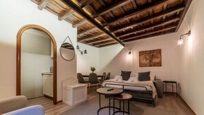 A cozy bedroom with a bed, bedside tables, a mirror, and a dining area with chairs and a table. - Quiet and cozy, by Campo de’ Fiori (Roma)