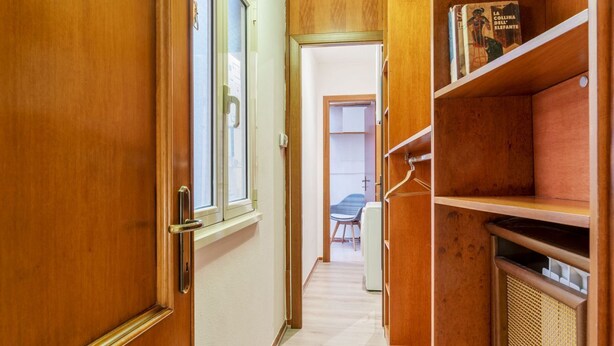 Un couloir avec des portes en bois, une bibliothèque et, au fond, un coin repas.