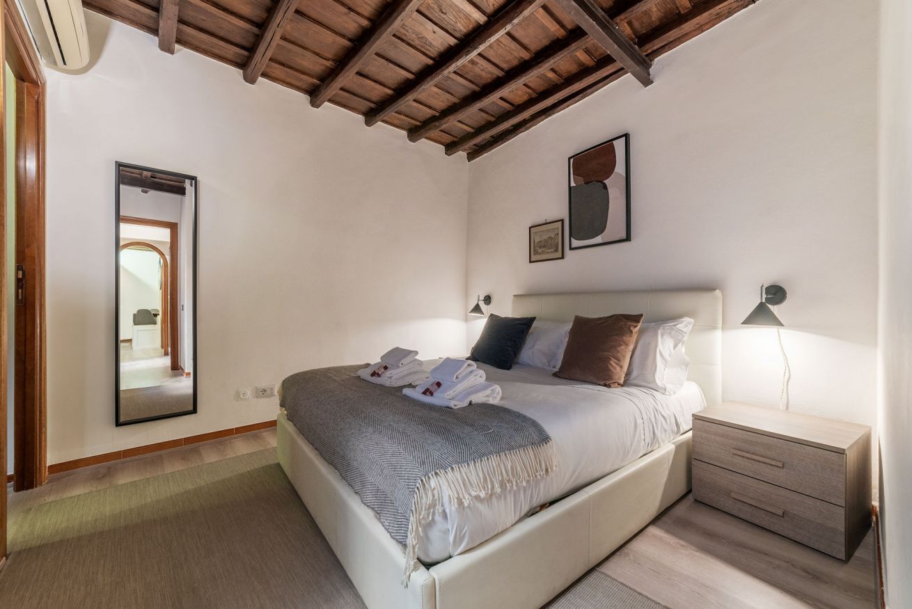 A bedroom with a bed, bedside table, and a mirror.