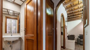 A wooden door leading to a bathroom with a sink and mirror. - Quiet and cozy, by Campo de’ Fiori (Roma)