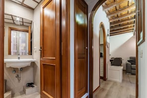 A wooden door leading to a bathroom with a sink and mirror.