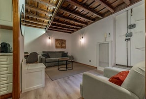 A modern living room with a wooden ceiling, a grey sofa, a small round table, and a white cabinet.