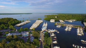 An aerial view of a marina with multiple docks, boats, and a large building with a swimming pool.