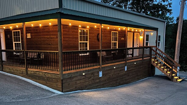A wooden building with a covered porch, a staircase, and a sign indicating a restaurant. - Grand Rivers, KY - Unit A - Cozy getaway with Cabin Charm near KY & Barkley Lake (Grand Rivers)