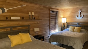 A room with two beds, wooden walls, a wooden ceiling, a wall-mounted anchor decoration, and a window with blinds. - Grand Rivers, KY - Unit A - Cozy getaway with Cabin Charm near KY & Barkley Lake (Grand Rivers)