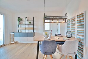 Uma cozinha moderna com uma ilha central, estantes embutidas e um espaço de refeições com duas cadeiras e uma mesa.