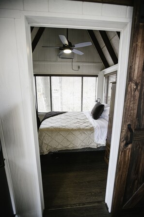 A bedroom with a bed, a ceiling fan, and a window with blinds.