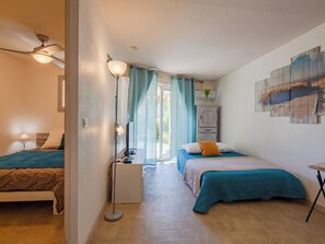 Quarto com duas camas, luminária de chão, escrivaninha e janela com cortinas.
