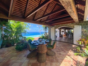 Dine al fresco with a view of the ocean from this outdoor dining area, featuring a round table and wicker chairs.