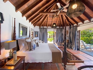 Relax in this serene bedroom with a large bed, wooden bench, and chair.