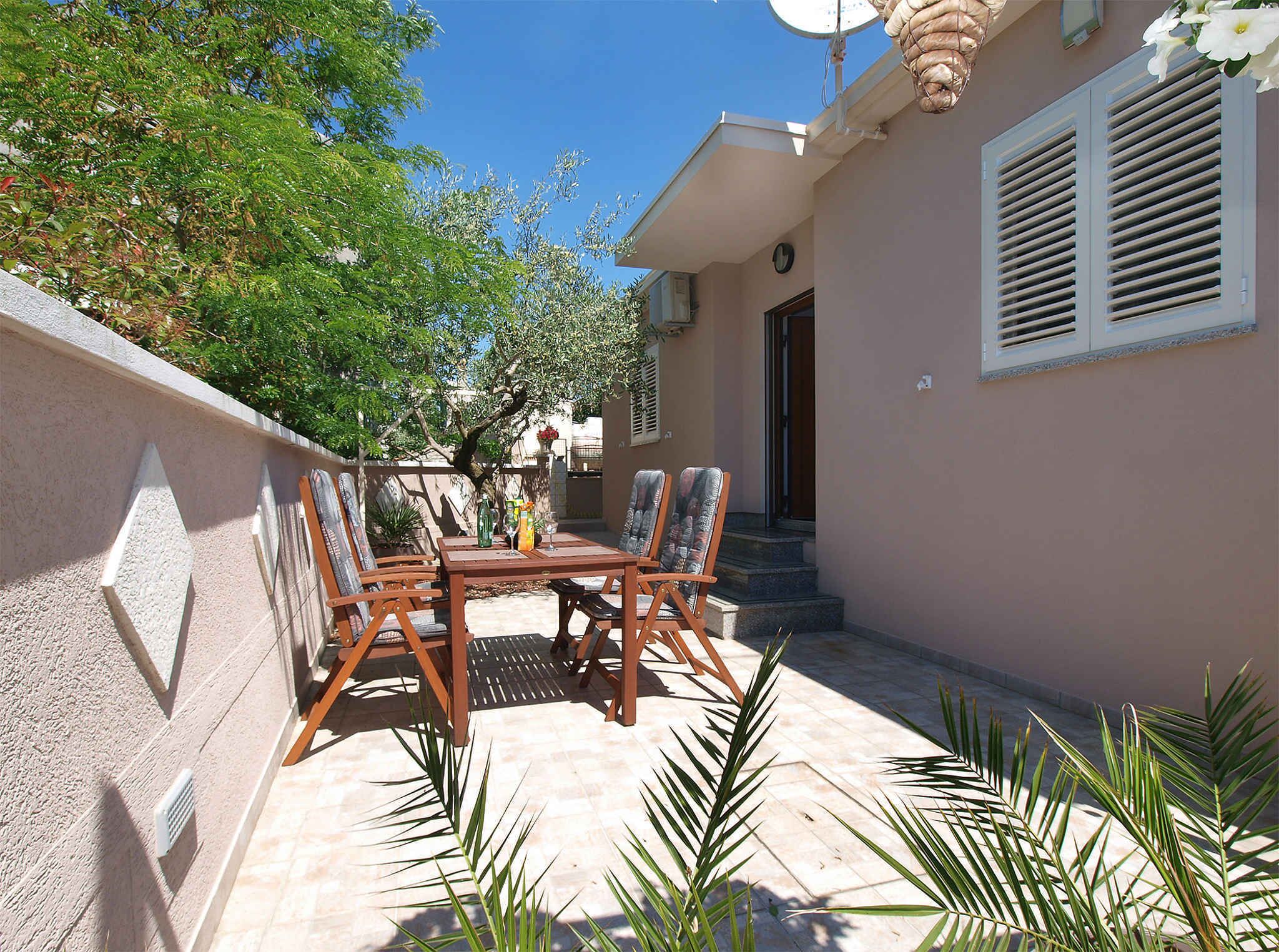 A patio with a table and chairs, a satellite dish, and a building with a door and window.