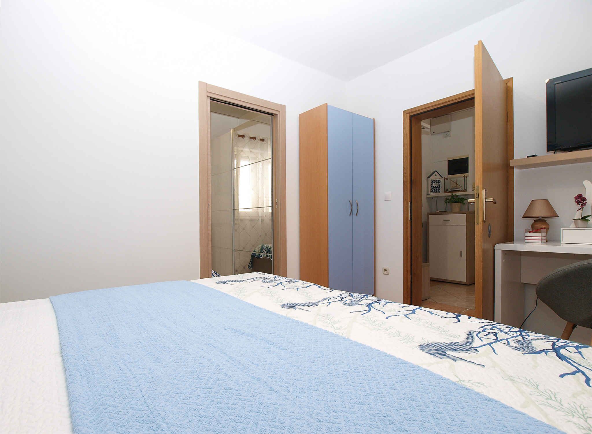 Une chambre à coucher comprenant un lit, une armoire, un bureau et un téléviseur.