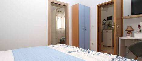 Une chambre à coucher comprenant un lit, une armoire, un bureau et un téléviseur.