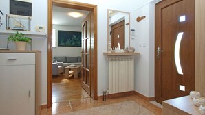 A hallway with a wooden door, a mirror, a radiator, and a small table with a plant. - Holiday home mit Klimaanlage und Terrasse (Vinkuran)