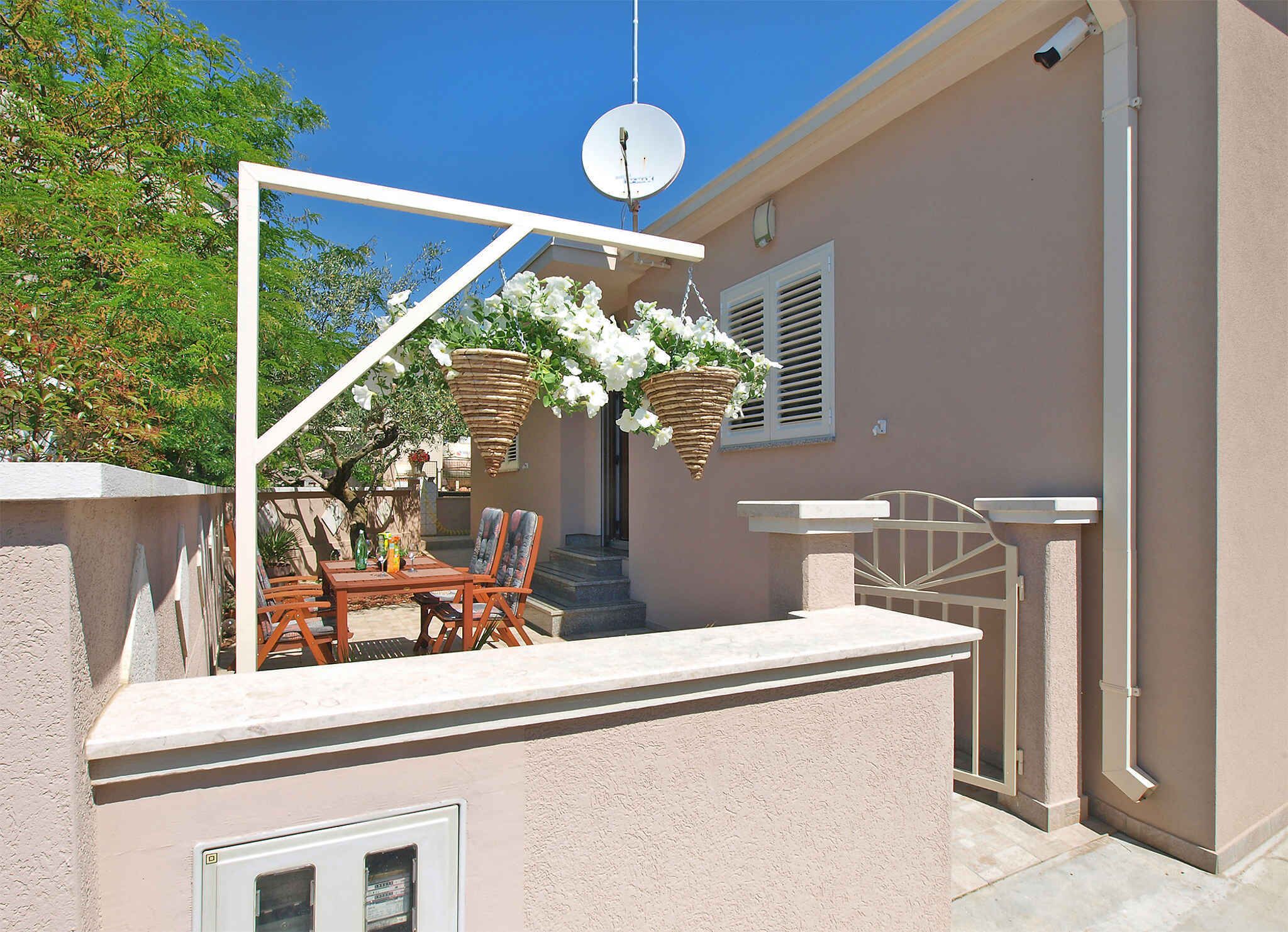 An outdoor patio with a table and chairs, a hanging flower basket, and a satellite dish.