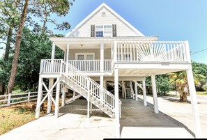 A two-story house with a porch and a staircase leading to the upper level. - 1 block to beach Pet friendly large deck & living space +plenty PK (Surfside Beach)