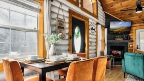 A cozy cabin interior with a dining area, a fireplace, and a television. - ☆Renovated Cabin☆ Hot Tub ◇ Fire Pit ◇ Fireplace ◇ Dog-friendly (Sevierville)