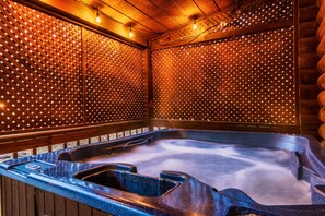 A hot tub with a wooden interior and a tiled wall with lights.