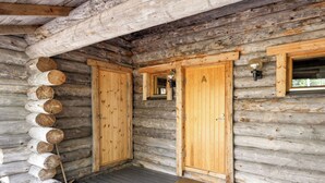 Een blokhut met twee houten deuren, een veranda en een raam met een lamp.