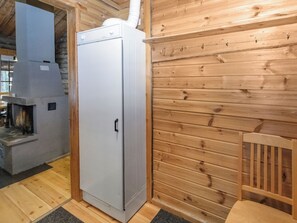 A compact, modern kitchen with a built-in refrigerator, a wood-burning stove, and a wooden wall.