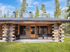 Une cabane en rondins avec une véranda, de grandes fenêtres et une cheminée.