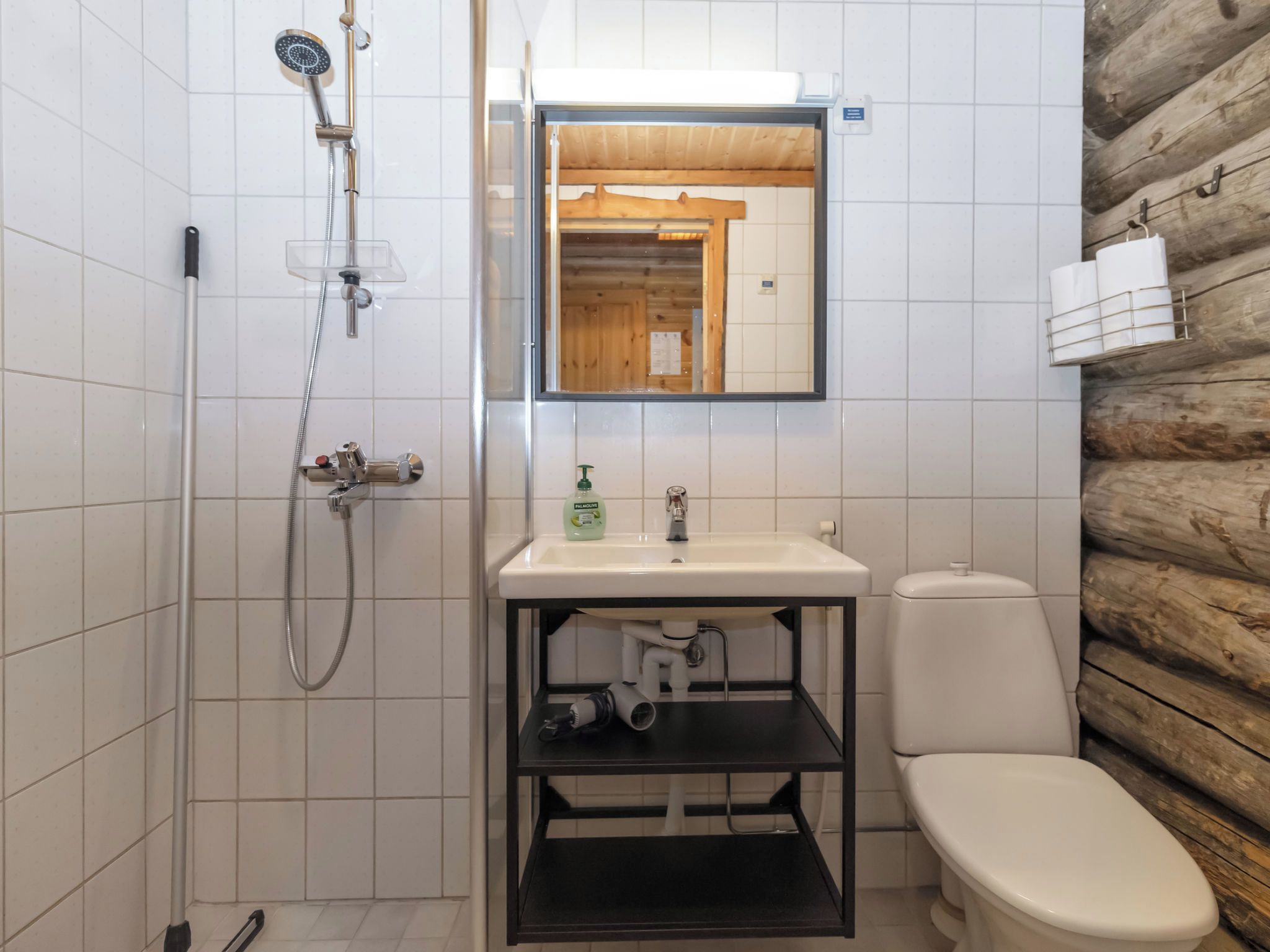 A bathroom with a shower, toilet, sink, and a mirror.