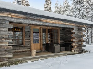 A log cabin with a wooden porch and a glass door.