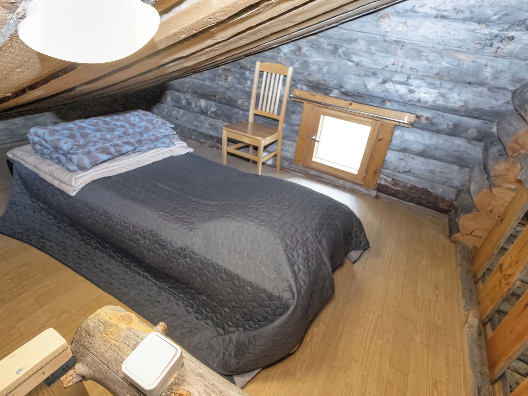 Ein gemütliches Schlafzimmer im Dachgeschoss mit einem Bett, einem Sessel und einem kleinen Holztisch.
