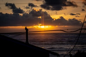 Un coucher de soleil sur l’océan, avec la silhouette d’une construction et des vagues.