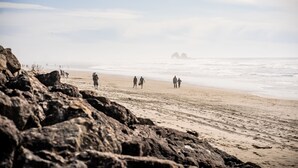 A beach with rocky foreground and people walking along the shore. - Family and pet friendly! 4 Bd, 3 bath beach house with ocean views! Sleeps 10! (Rockaway Beach)