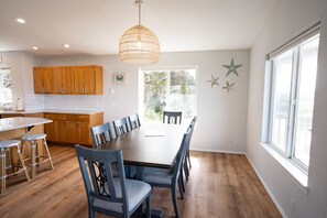 Une cuisine moderne avec des meubles en bois, une table à manger et des tabourets de bar.