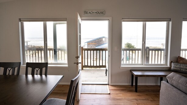 A room with a view of the beach, a sign reading "Beach House", and a wooden deck outside. - Family and pet friendly! 4 Bd, 3 bath beach house with ocean views! Sleeps 10! (Rockaway Beach)