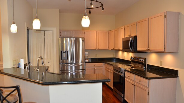 A modern kitchen with stainless steel appliances, wooden cabinets, and a central island. - Charming Lakeview House, 15 minute drive to downtown Naples beaches and 5th Ave. (Naples)