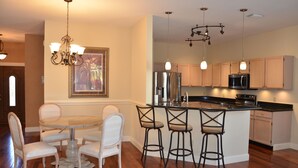 A modern kitchen with a central island, bar stools, stainless steel appliances, and pendant lighting. - Charming Lakeview House, 15 minute drive to downtown Naples beaches and 5th Ave. (Naples)