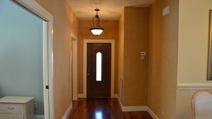 A hallway with a wooden floor, a door with a window, and a light fixture above it. - Charming Lakeview House, 15 minute drive to downtown Naples beaches and 5th Ave. (Naples)