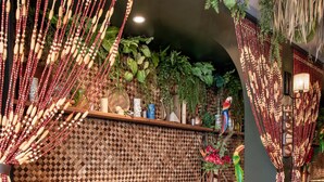 L’intérieur d’un restaurant avec des tables et des bancs en bois, un mur orné de motifs et des décorations suspendues.