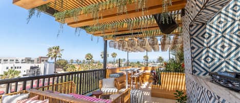 Una terraza en la azotea con mobiliario de madera, plantas colgantes y baldosas estampadas.