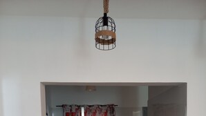 Keittiössä on marmorinen työtaso, vedenkeitin, roskakori ja ikkuna, jossa on punakukkaiset verhot.