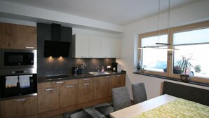 A modern kitchen with wooden cabinets, a built-in microwave, and a window with a view of the outside. - Apartment Nina by Interhome (Hippach)
